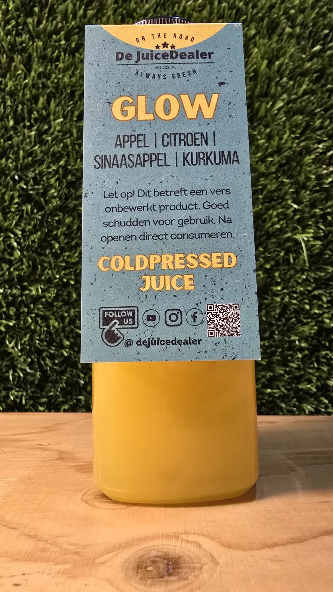 Glow Cold-Pressed Juice met productlabel, waarop de ingrediΓ«nten appel, citroen, sinaasappel en kurkuma duidelijk zichtbaar zijn.