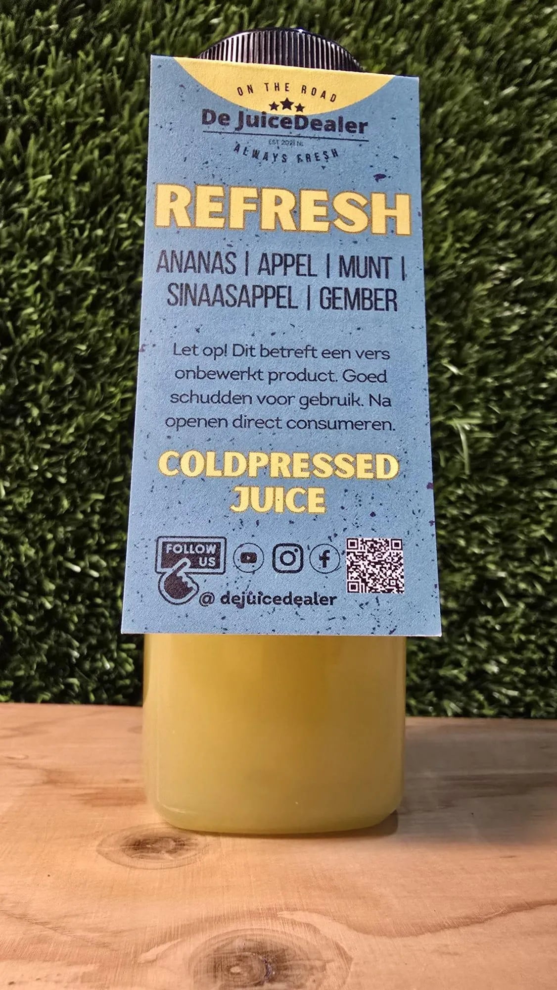 "Fles 'Refresh' cold-pressed juice met een label waarop de ingrediënten staan: ananas, appel, munt, sinaasappel en gember."
